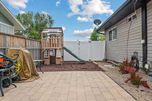 View of patio featuring a playground and a fenced backyard