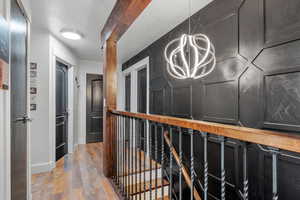 Hallway with a chandelier, light wood-style floors, and a textured ceiling