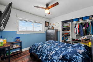 Bedroom featuring wood finished floors, wainscoting, a closet, ceiling fan, and baseboards