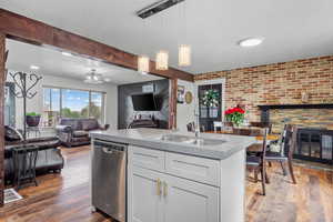 Kitchen with dishwasher, open floor plan, a textured ceiling, a sink, and hardwood / wood-style flooring