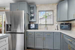 Kitchen featuring stainless steel fridge, black microwave, light countertops, and a textured ceiling