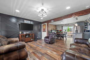 Living room with wood finished floors, a textured ceiling, recessed lighting, and a decorative wall