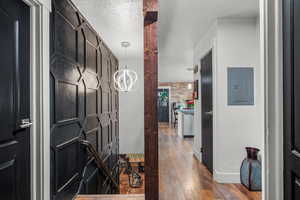 Hallway featuring electric panel, hardwood / wood-style flooring, and baseboards