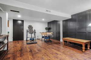 Exercise area with a decorative wall, wood finished floors, a textured ceiling, and baseboards