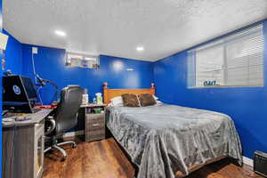 Bedroom with a textured ceiling, wood finished floors, baseboards, and recessed lighting