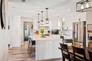 Kitchen featuring stainless steel refrigerator with ice dispenser, light wood finished floors, white cabinetry, backsplash, and recessed lighting