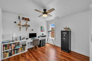 Office featuring a ceiling fan, baseboards, wood finished floors, and a textured ceiling