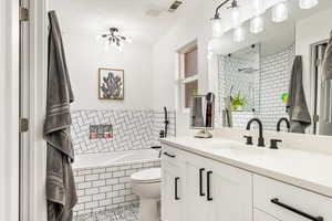 Full bath with tiled bath, vanity, tile patterned floors, toilet, and a tile shower