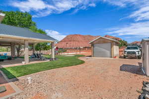 View of yard featuring a playground, ceiling fan, an outdoor structure, a mountain view, and a patio area