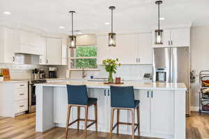 Kitchen featuring appliances with stainless steel finishes, custom range hood, a kitchen island, white cabinets, and recessed lighting