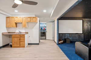 Kitchen featuring washer / dryer, a sink, light wood-style floors, light brown cabinets, and baseboards