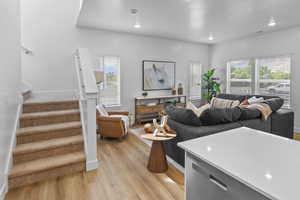 Living room featuring light wood finished floors, stairs, recessed lighting, and baseboards
