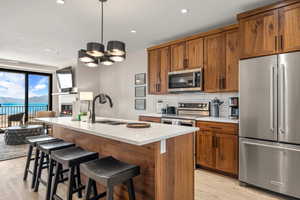 Kitchen with stainless steel appliances, a sink, light wood-style flooring, brown cabinetry, and recessed lighting