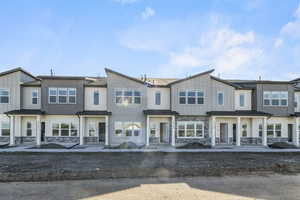 Townhome / multi-family property featuring stone siding and board and batten siding