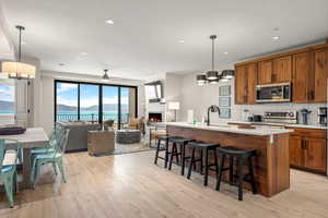 Kitchen featuring stainless steel appliances, brown cabinetry, a sink, light wood-style floors, and open floor plan