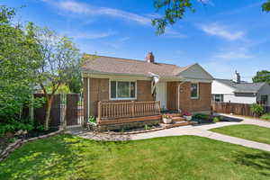 View of front of property with brick siding, a chimney, roof with shingles, and covered porch