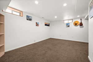 Below grade area with recessed lighting, dark colored carpet, and baseboards