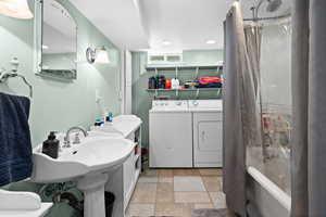 Bathroom with separate washer and dryer, stone finish floors, recessed lighting, and shower / bath combo with shower curtain