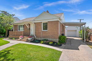 View of front of home with an outbuilding, a front yard, brick siding, driveway, and a garage
