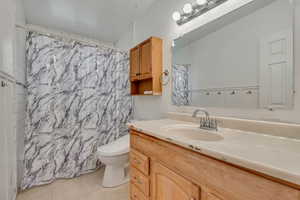 Bathroom with tile patterned floors, toilet, vanity, and a shower with curtain