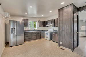 Kitchen featuring stainless steel appliances, under cabinet range hood, dark brown cabinets, baseboards, and recessed lighting