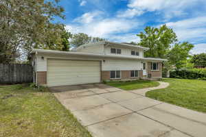 Split level home with brick siding, a garage, and concrete driveway