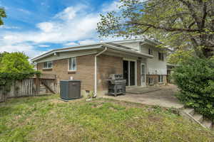 Rear view of property featuring central AC unit, brick siding, and a patio