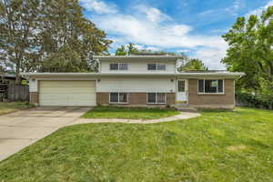 Split level home featuring brick siding, a garage, and concrete driveway