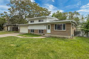Split level home featuring brick siding, concrete driveway, a garage, and entry steps