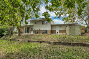 Back of property with brick siding, fence, and a shed