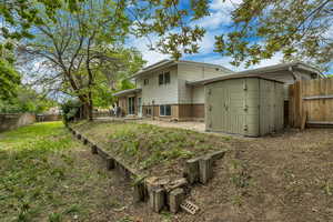 Rear view of house with brick siding, a patio area, fence, and a shed