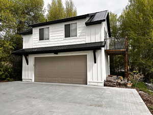 Modern farmhouse style home featuring board and batten siding, an attached garage, metal roof, and driveway