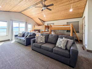Living room featuring wooden ceiling, carpet flooring, lofted ceiling, baseboards, and ceiling fan