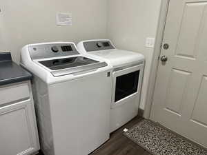 Washroom featuring separate washer and dryer, dark wood finished floors, and cabinet space