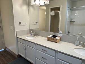 Bathroom with a shower with shower door, wood finished floors, and vanity