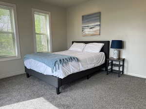 Carpeted bedroom with multiple windows and baseboards
