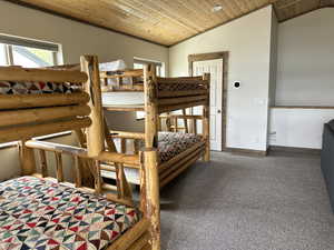 Carpeted bedroom with wooden ceiling, lofted ceiling, and baseboards