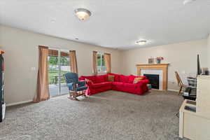 Living room with carpet, a tile fireplace, a textured ceiling, and baseboards