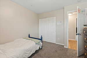 Carpeted bedroom featuring a closet and baseboards