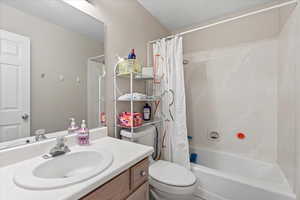 Bathroom with toilet, shower / bath combo with shower curtain, and vanity