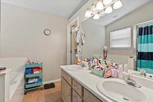 Bathroom with a bath, tile patterned floors, double vanity, and a shower with shower curtain
