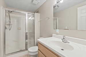 Bathroom featuring toilet, a stall shower, vanity, and tile patterned floors
