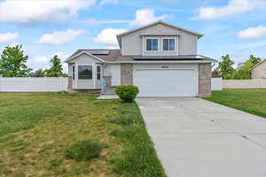 View of front of property featuring an attached garage, roof mounted solar panels, concrete driveway, and brick siding