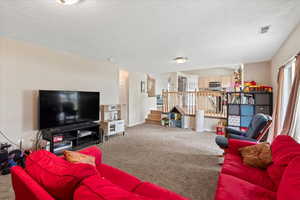 Carpeted living area featuring stairs, a textured ceiling, and baseboards