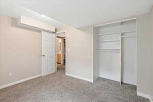 Unfurnished bedroom with carpet flooring, a closet, and baseboards