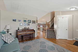 Living area featuring wood finished floors, stairway, baseboards, and vaulted ceiling