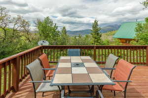 Wooden terrace featuring outdoor dining space and a mountain view