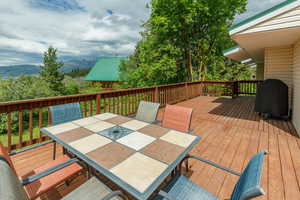 Wooden deck with outdoor dining space, a mountain view, and area for grilling
