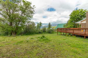 View of grassy yard featuring a deck with mountain view