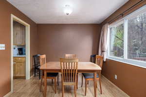Dining area featuring light wood-style floors, plenty of natural light, baseboards, and a textured ceiling